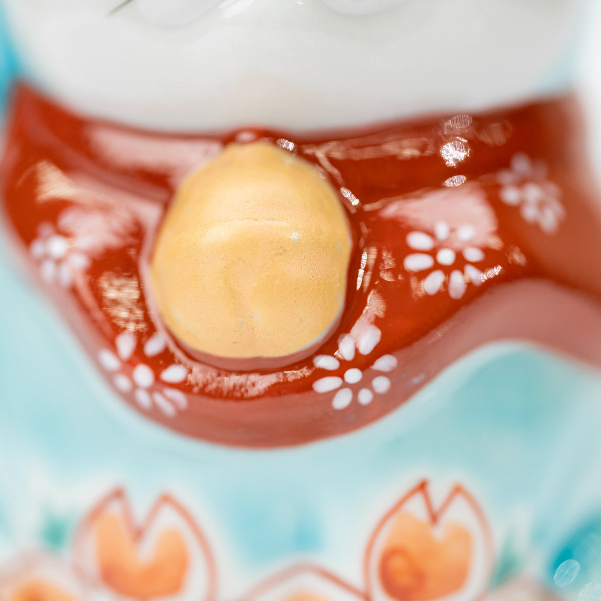 Close-up of the red floral bib and gold-colored bell on the lucky cat