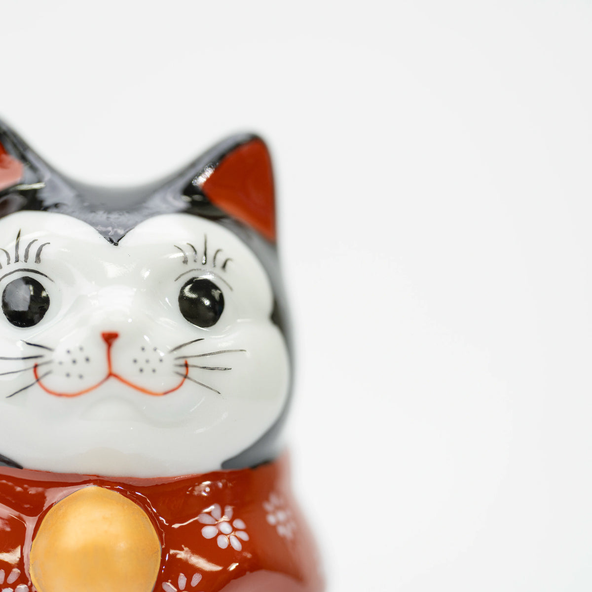 Close-up of the lucky cat's white face, black eyes, and red inner ears