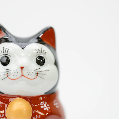 Close-up of the lucky cat's white face, black eyes, and red inner ears