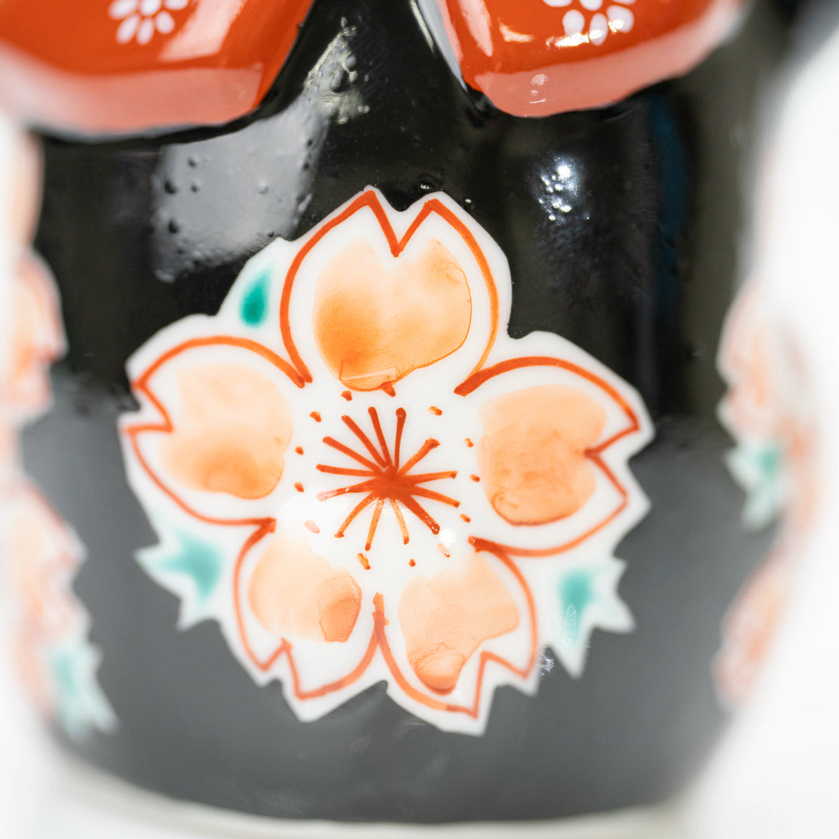 Close-up of one cherry blossom with peach-colored petals against black glaze