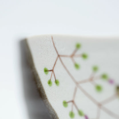 Close-up of a green branch with small painted dots