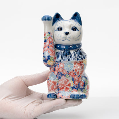 Chat porte-bonheur bleu en porcelaine Seto, tenu dans une main gantée pour montrer sa taille