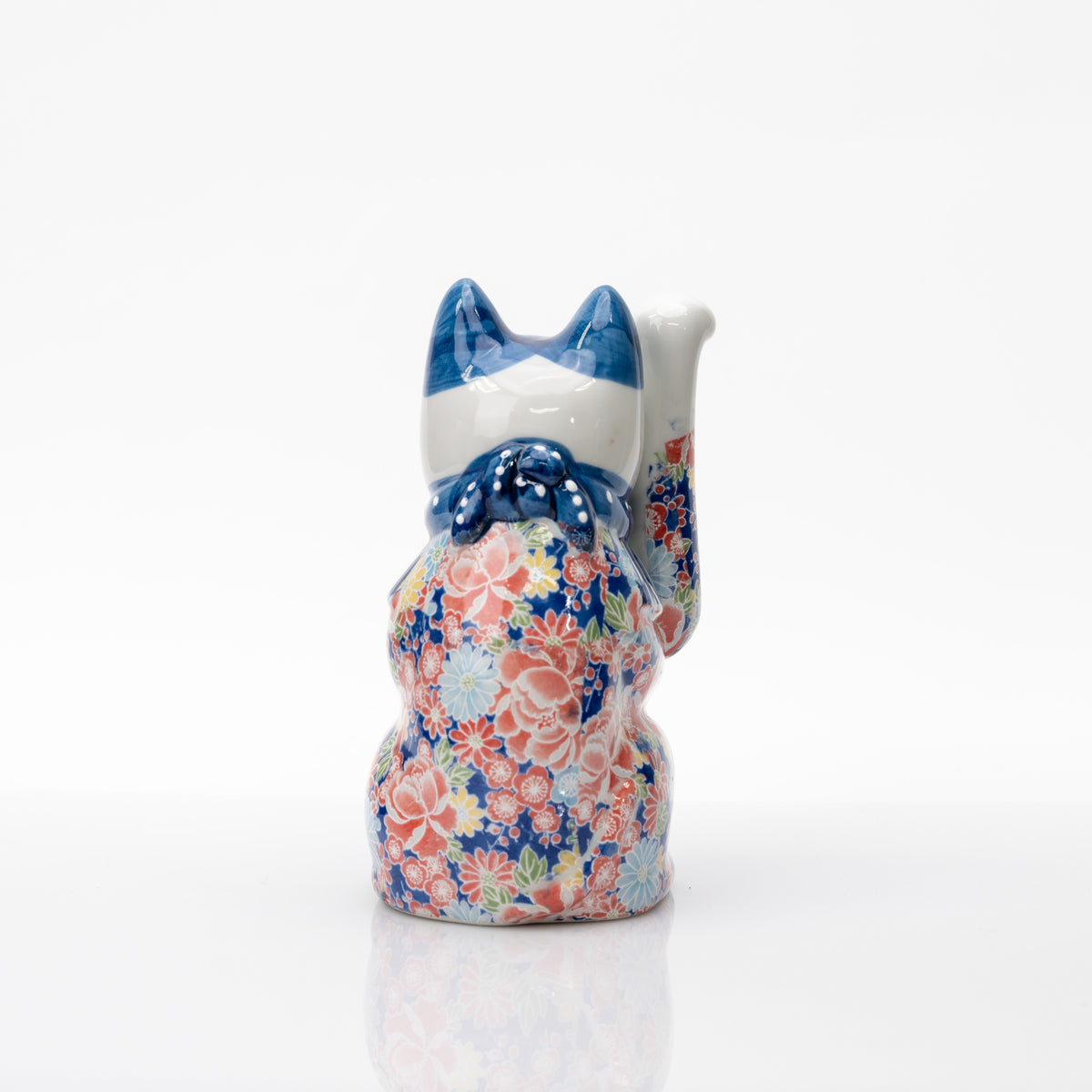 Dos du chat bleu à décor floral, montrant le nœud bleu moulé, la tête blanche et la patte levée