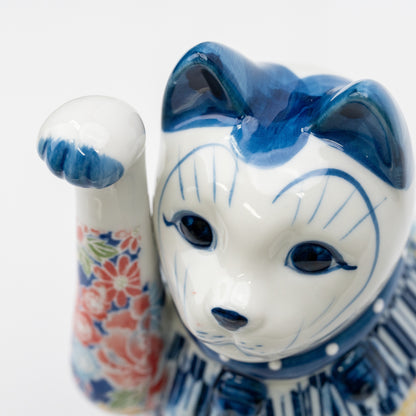 Gros plan sur le visage blanc, les oreilles bleues, les yeux et la patte levée du chat à décor floral