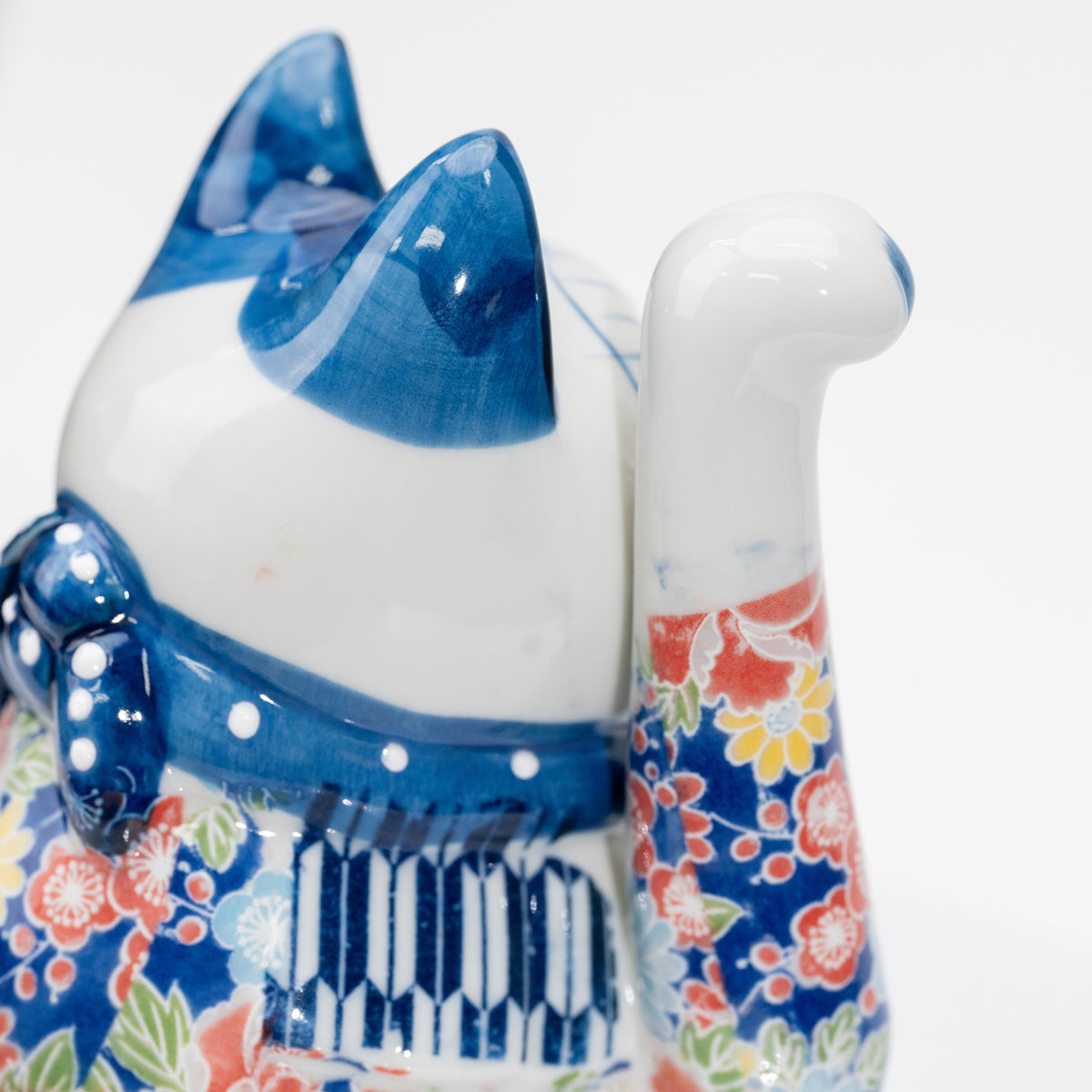 Détail de l’oreille bleue, de la patte droite levée, du motif floral et du plastron rayé, vus de profil