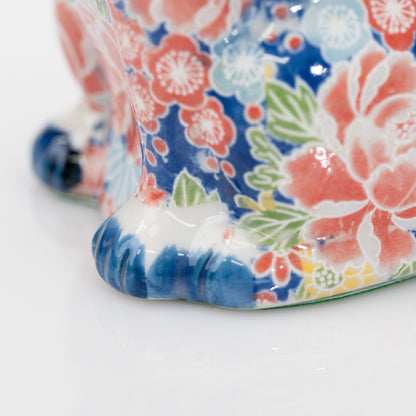 Gros plan sur le décor floral et les pattes bleues près de la base du chat en porcelaine