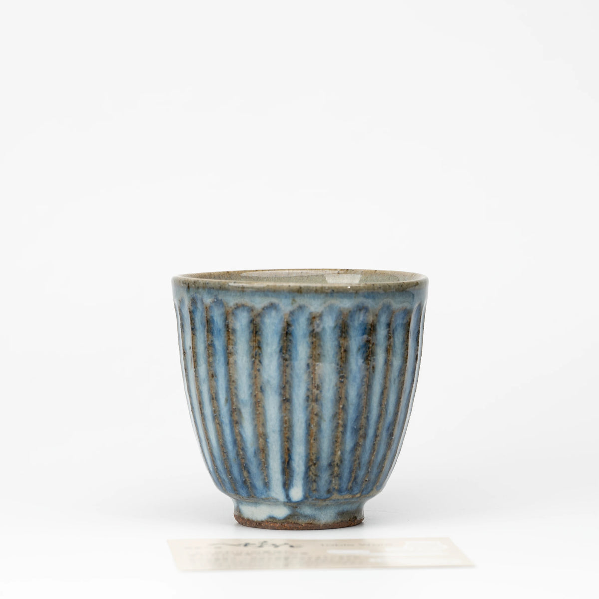 Ribbed blue-grey tea cup, whole view on a neutral background.