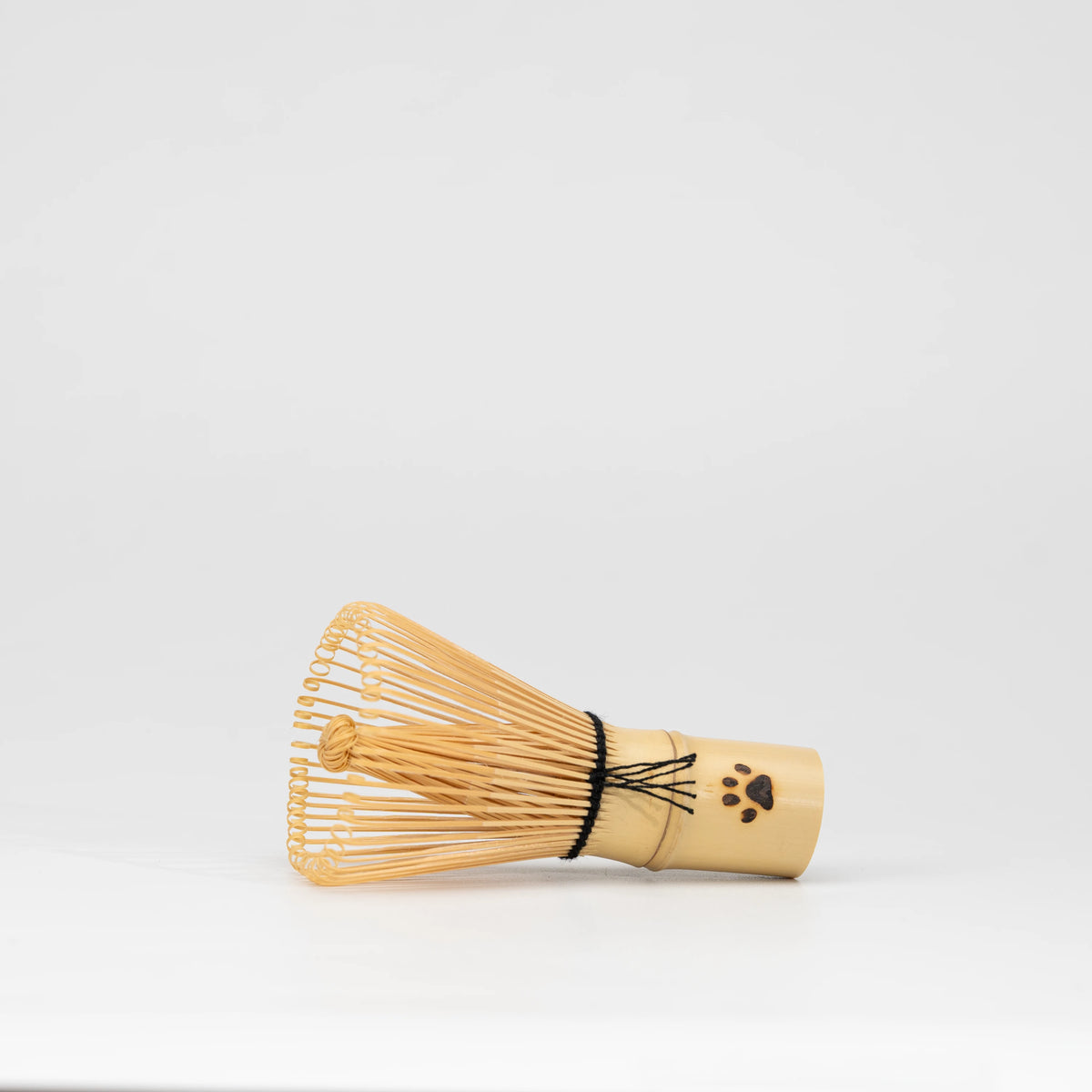 Paw-print bamboo mini whisk, side view showing the shape and surface.