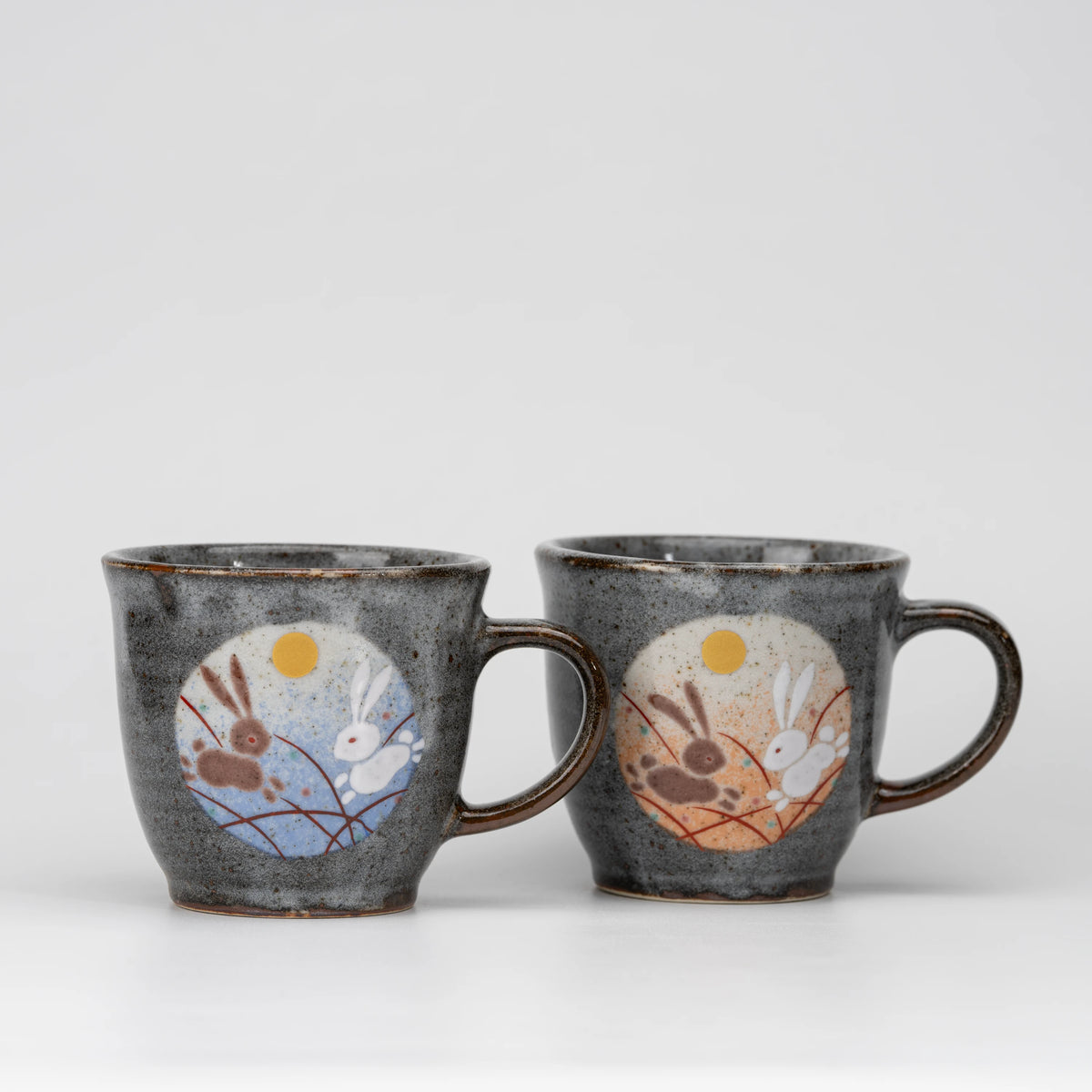 Rabbit and moon mug pair, whole view on a neutral background.