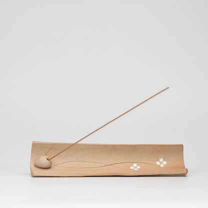 Brown floral incense holder, side view showing the shape and surface.