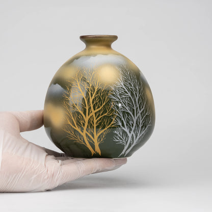 Olive green tree motif bud vase, held in a hand to show scale.