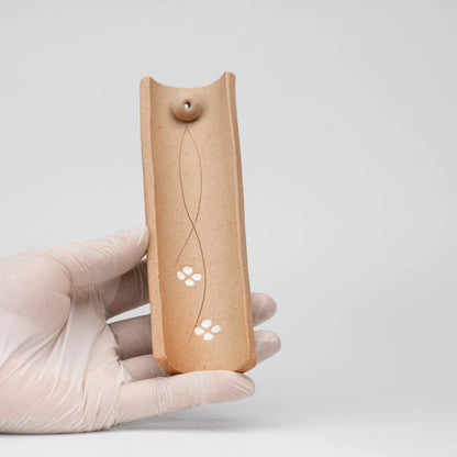 Brown floral incense holder, held in a hand to show scale.