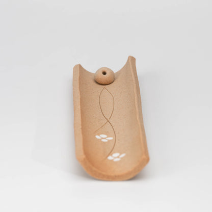 Brown floral incense holder, held in a hand to show scale.