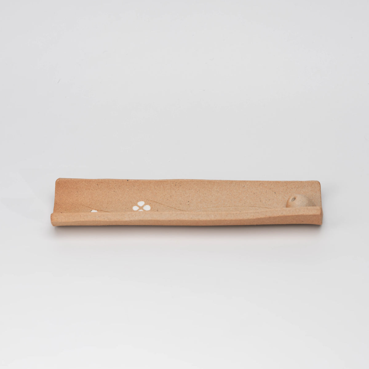Brown floral incense holder, side view showing the shape and surface.