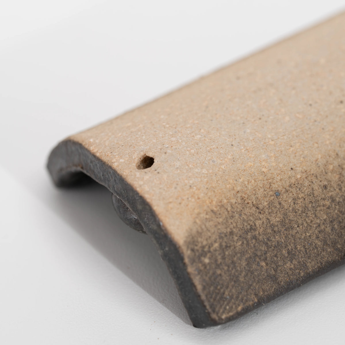 Brown floral incense holder, curved underside and small hole.