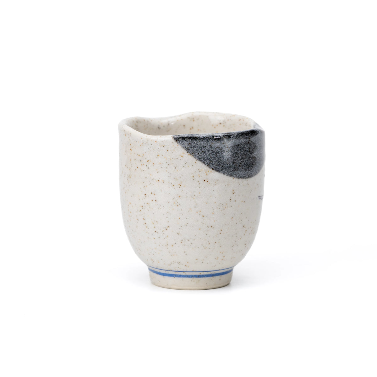 Back of the speckled cream yunomi, showing the dark gray rim accent and blue lines around the foot.