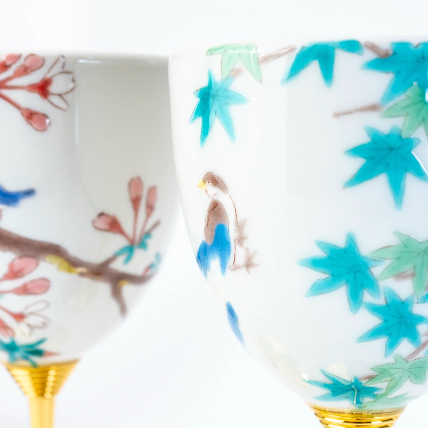Close-up of Kutani wine cups with hand-painted bird, blossom, and maple leaf motifs