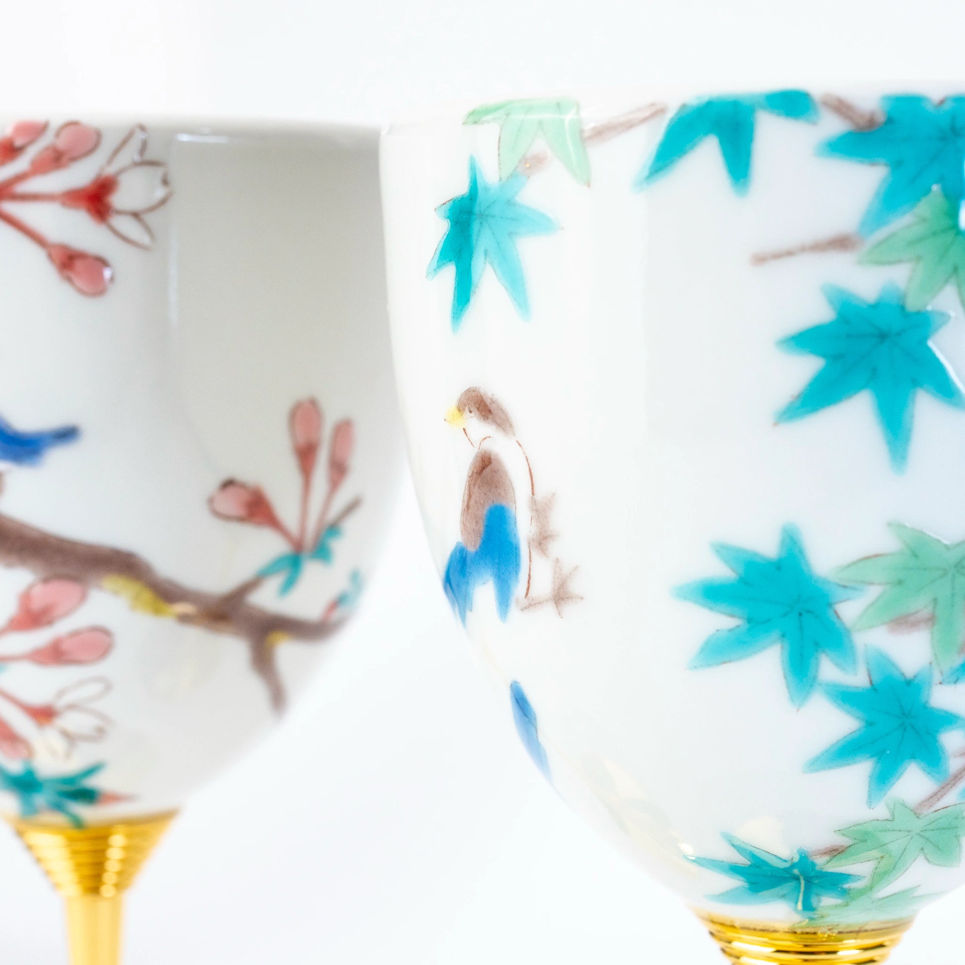 Close-up of Kutani wine cups with hand-painted bird, blossom, and maple leaf motifs