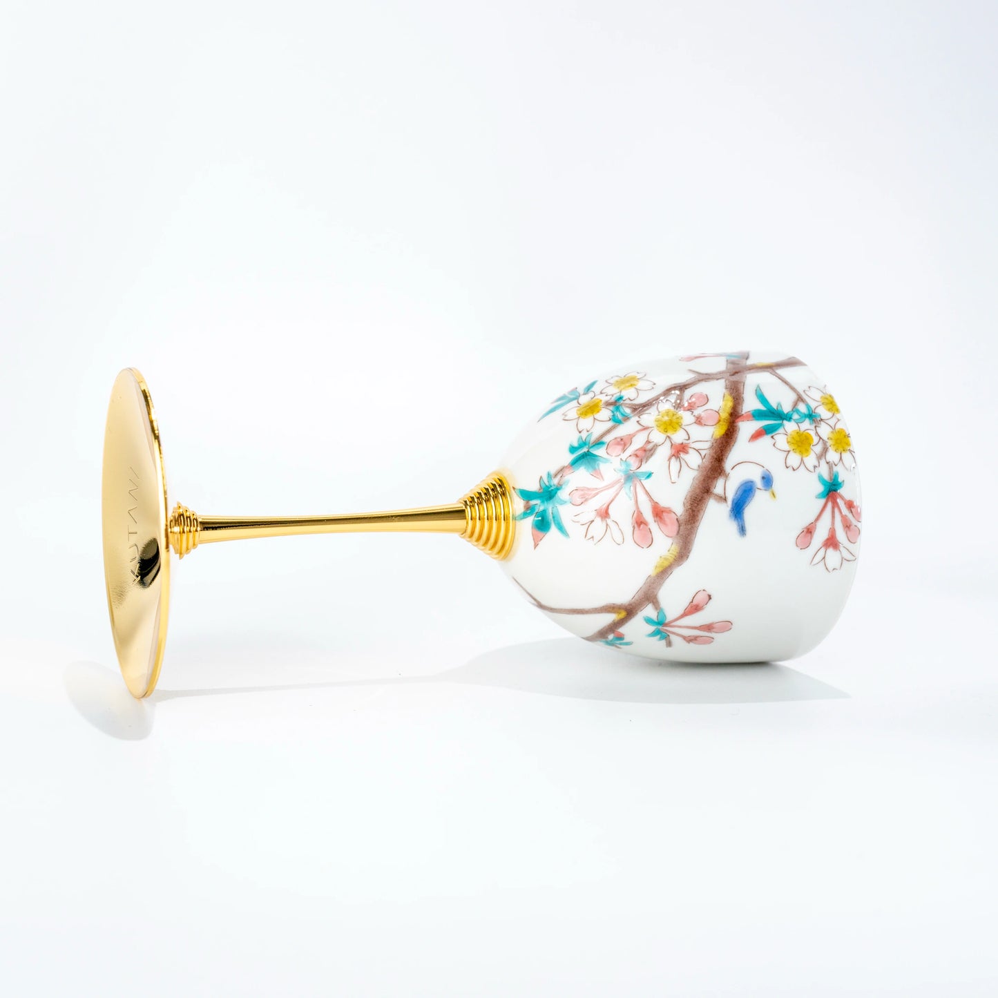 Reverse side view of a Kutani porcelain wine cup laid on its side showing the painted bowl and gold