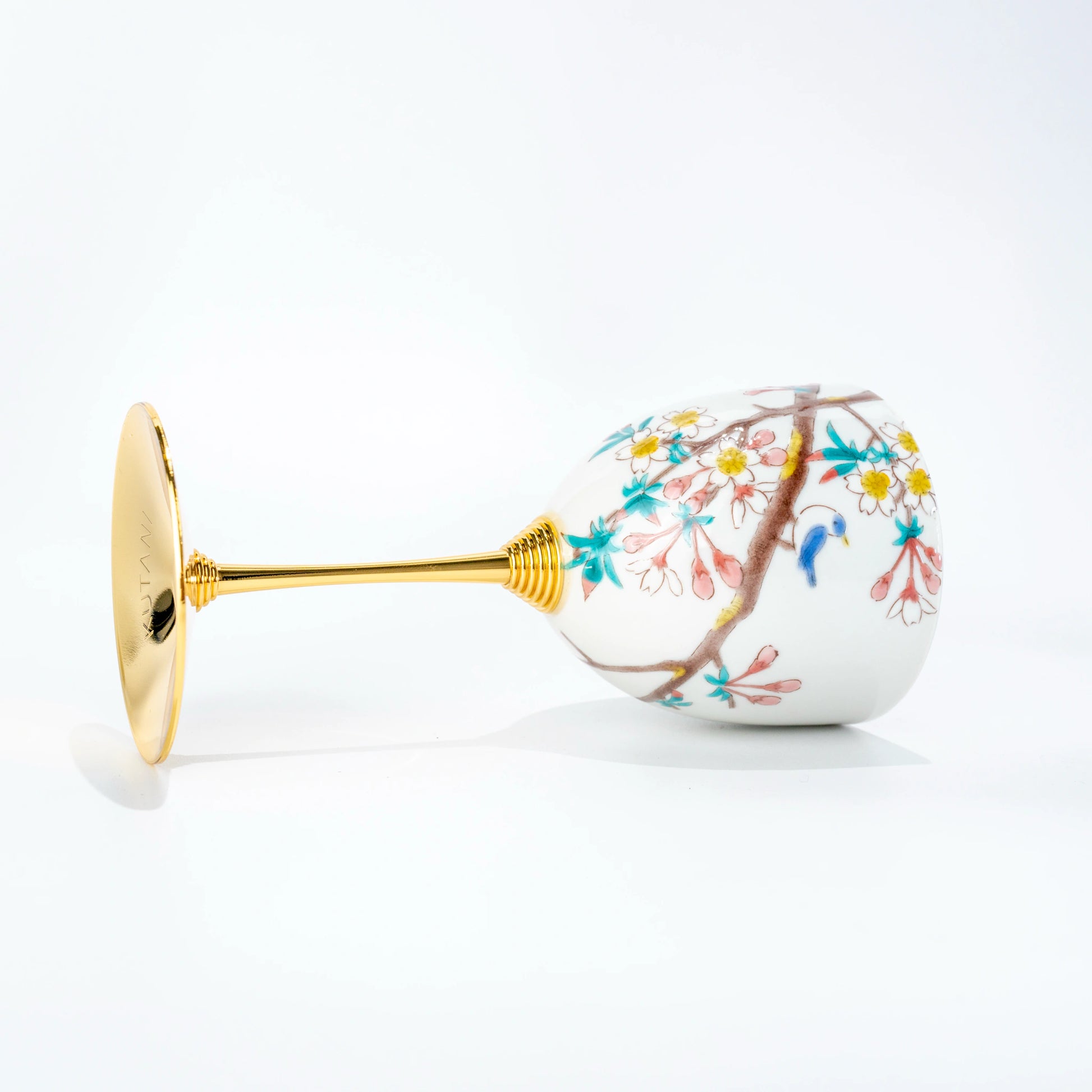Reverse side view of a Kutani porcelain wine cup laid on its side showing the painted bowl and gold