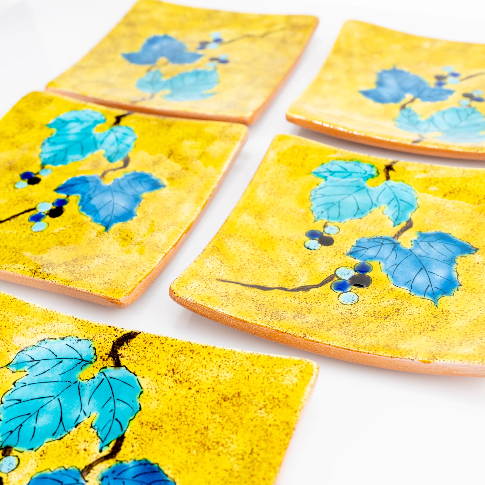 Four Kutani wild grape square plates arranged in a flat lay