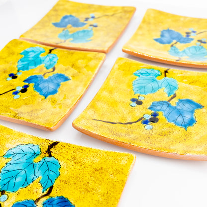 Four Kutani wild grape square plates arranged in a flat lay