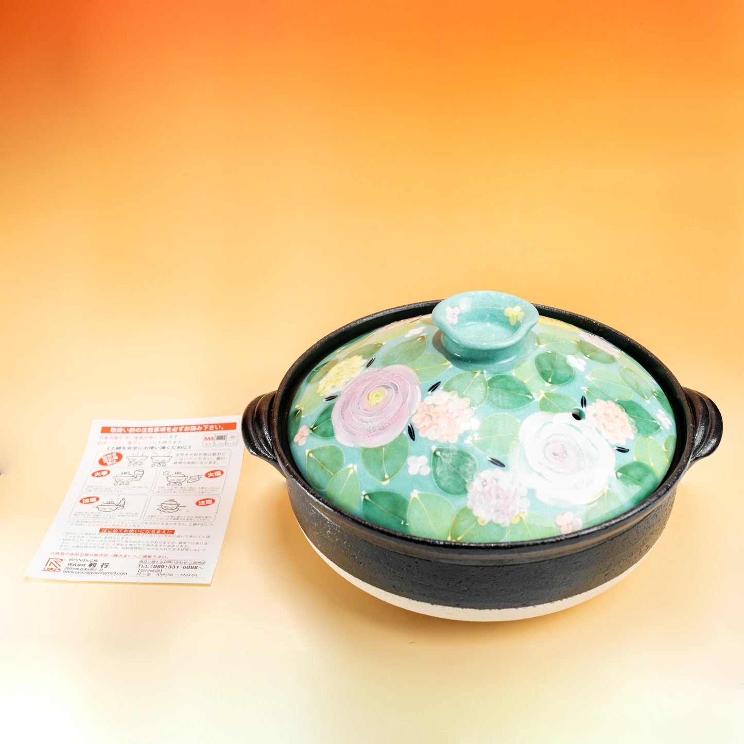 Japanese donabe clay pot with a pastel floral porcelain lid and black pottery base