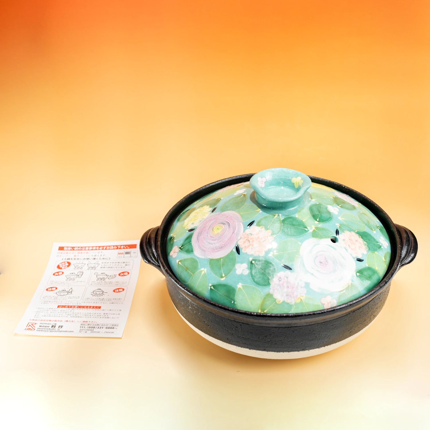 Japanese donabe clay pot with a pastel floral porcelain lid and black pottery base