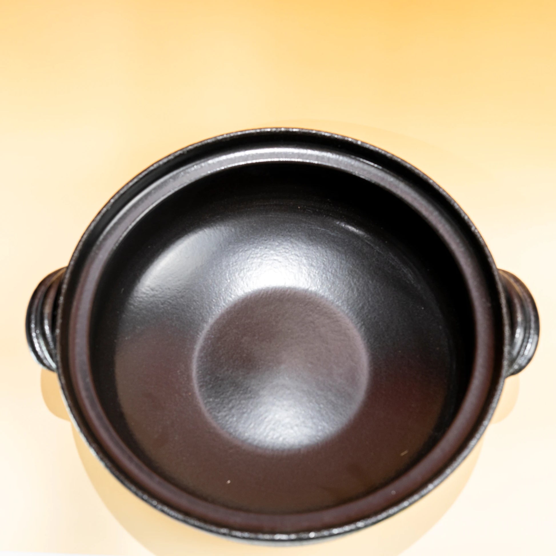 Top view of a Japanese donabe clay pot showing the dark interior and side handles