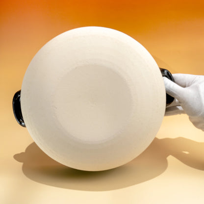 Hand-held underside view of the white porcelain lid for a Japanese donabe clay pot
