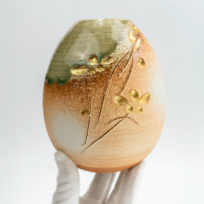 Handheld view of handmade Japanese pottery vase with green glaze