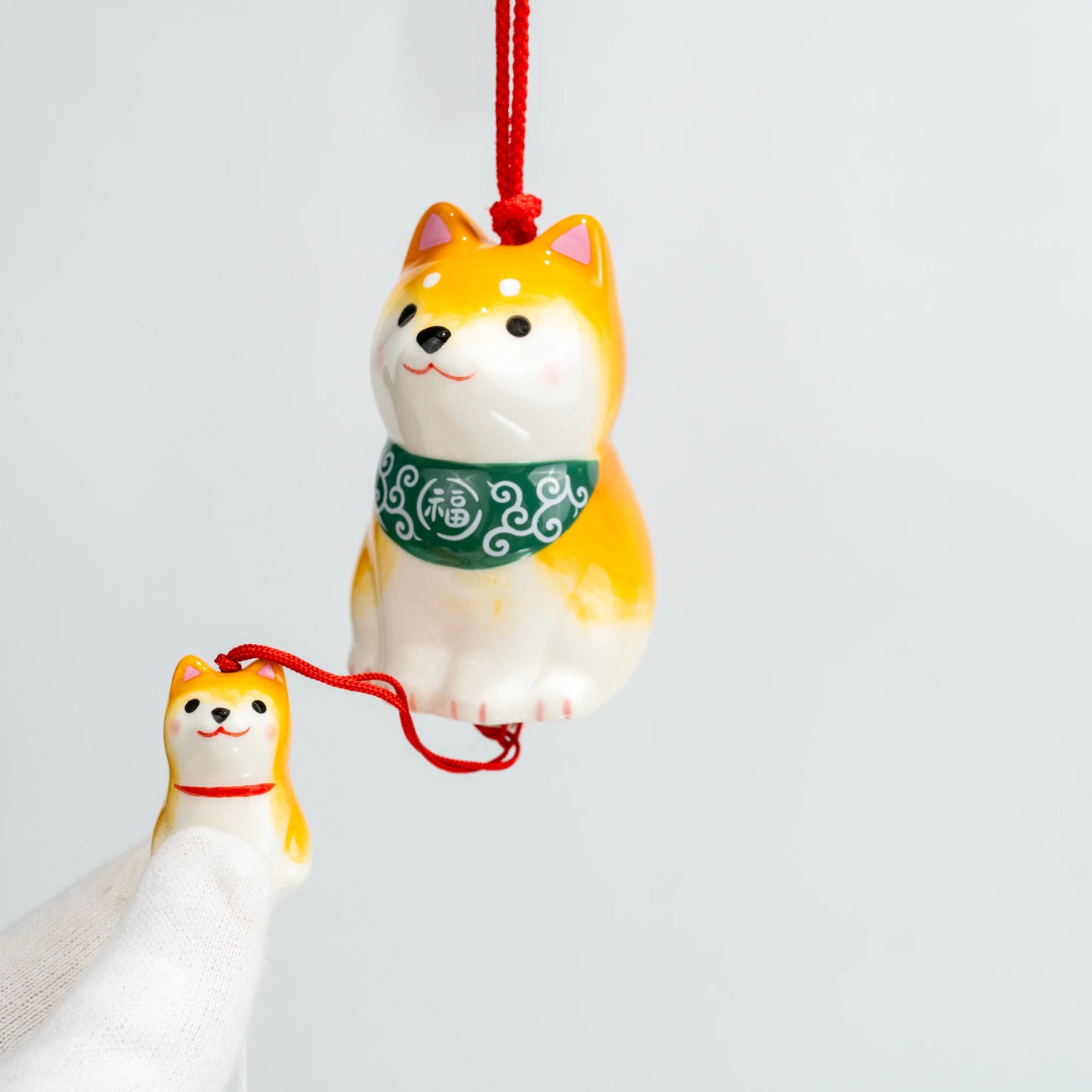 Angled close-up of ceramic Shiba wind chime with puppy charm