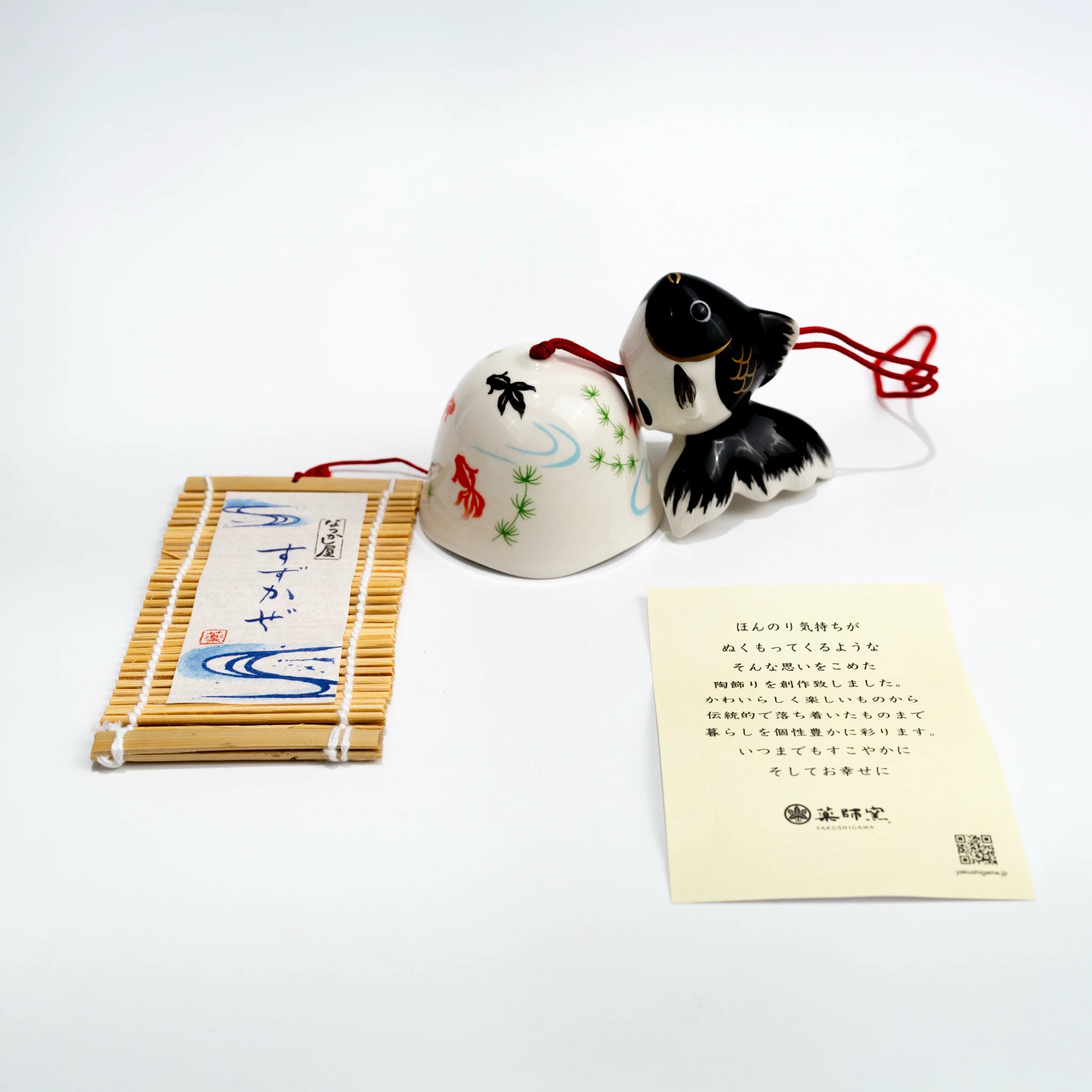 Flat lay of black goldfish wind chime with paper strip and included card