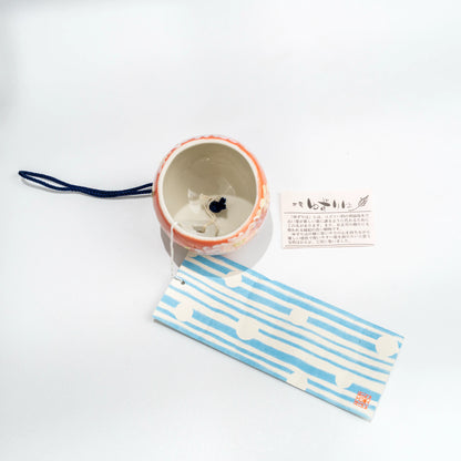 Top and underside view of floral ceramic wind chime with blue strip and tag
