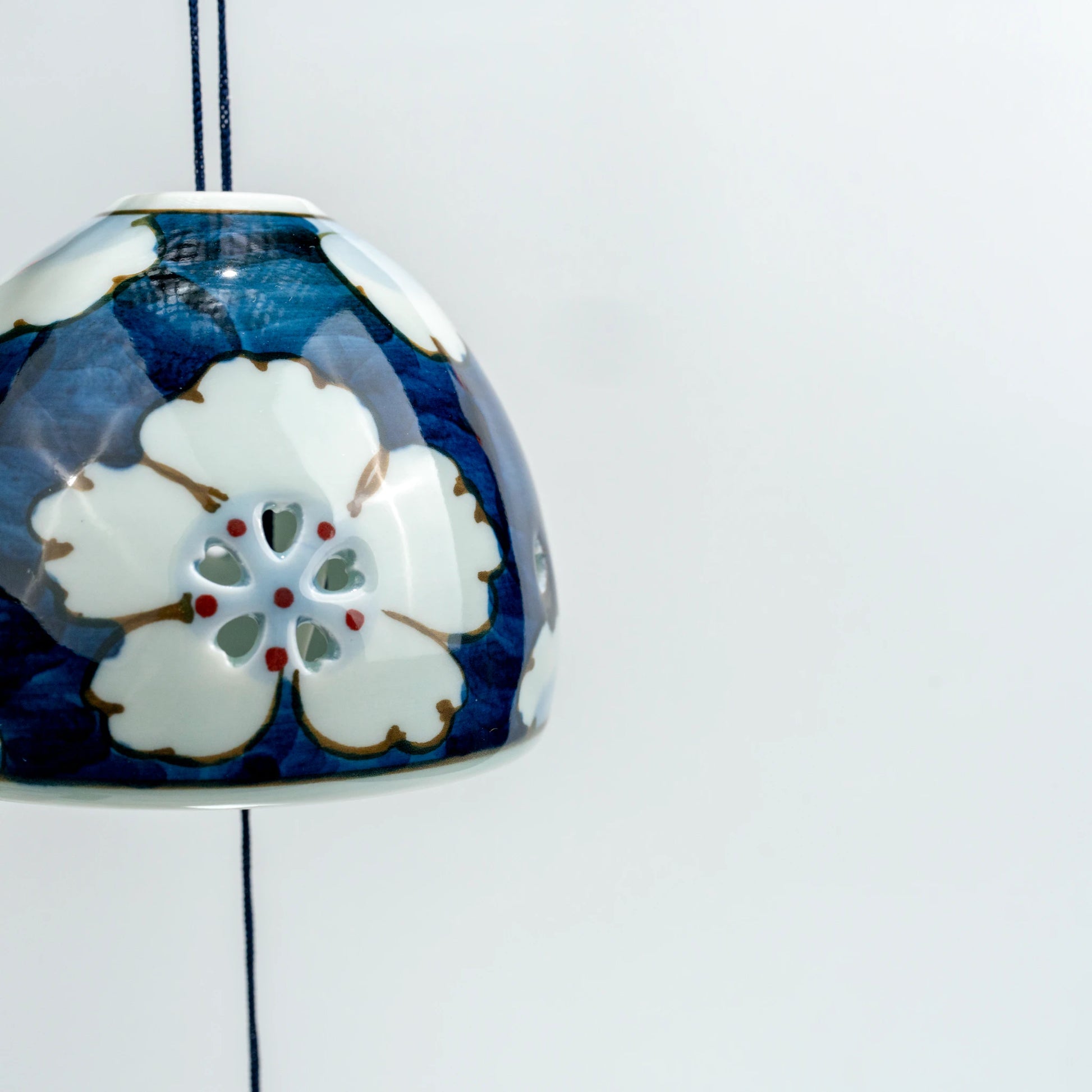 Close side hanging view of Arita floral openwork wind chime showing hand-painted design