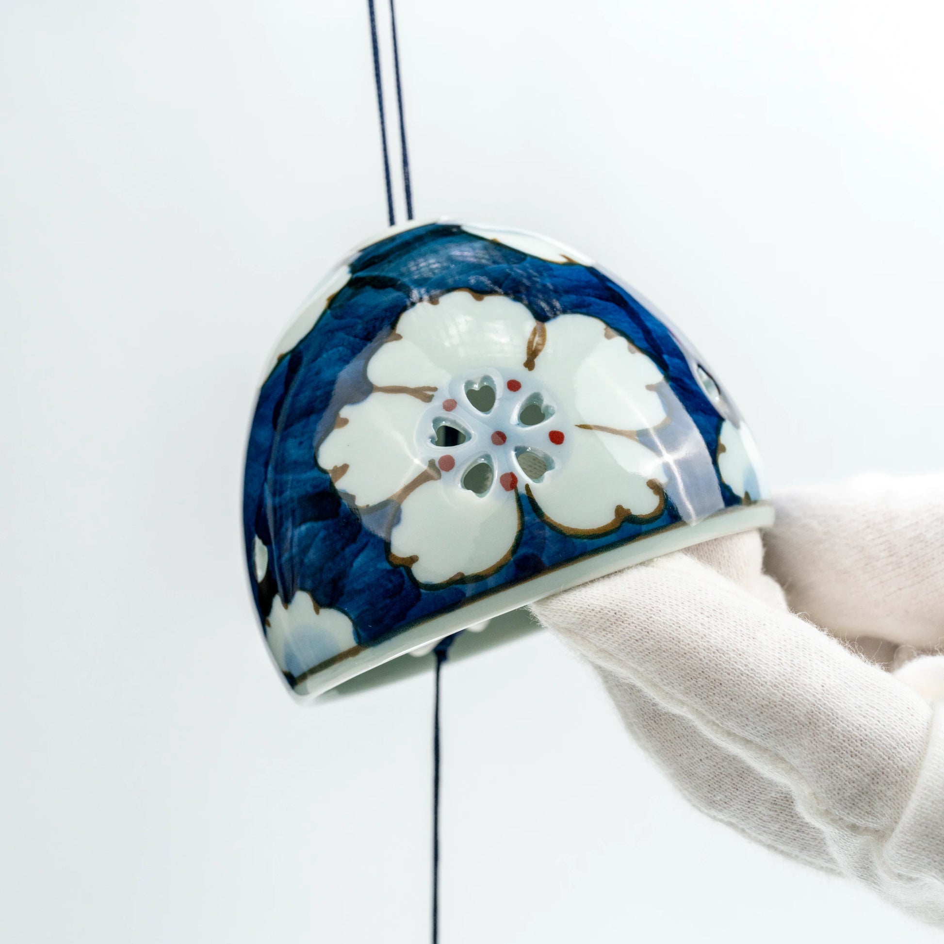 Detail view of Arita floral openwork wind chime showing painted floral pattern and paper clapper