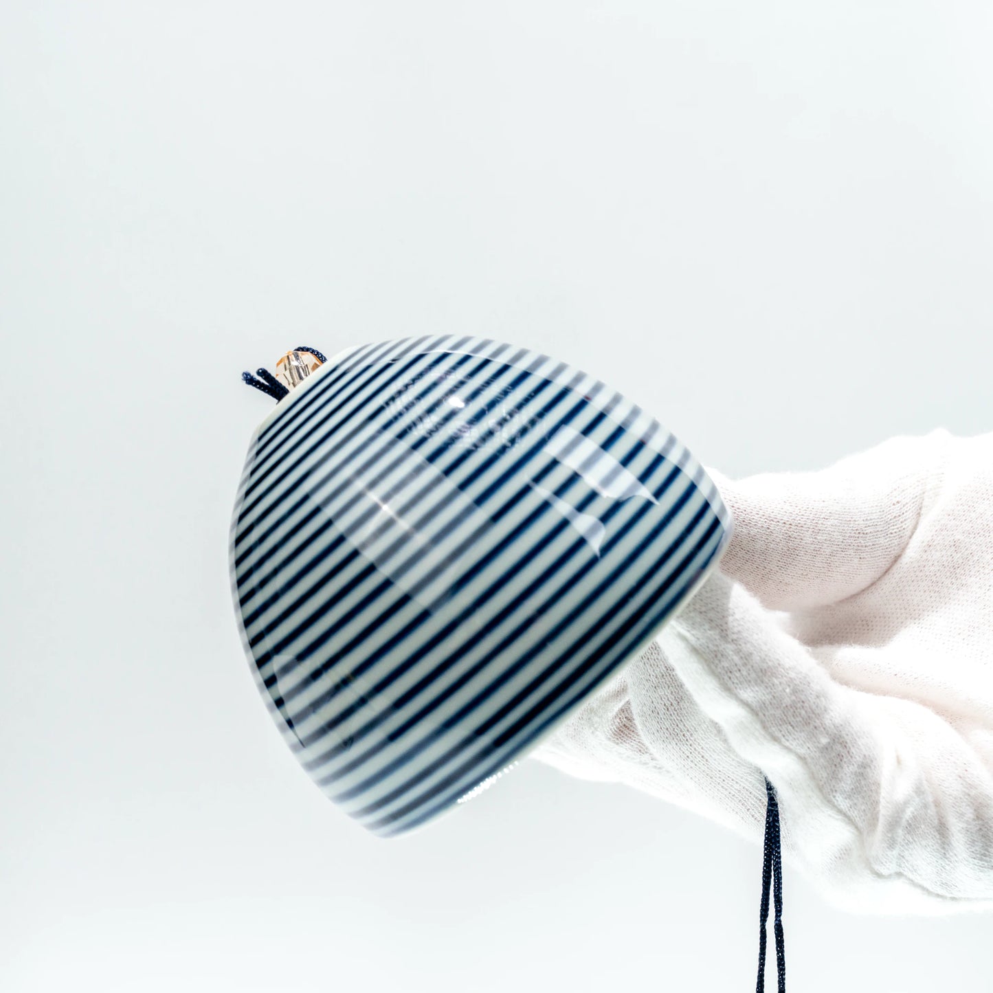 Angled side view of Japanese stripe ceramic furin bell held in hand
