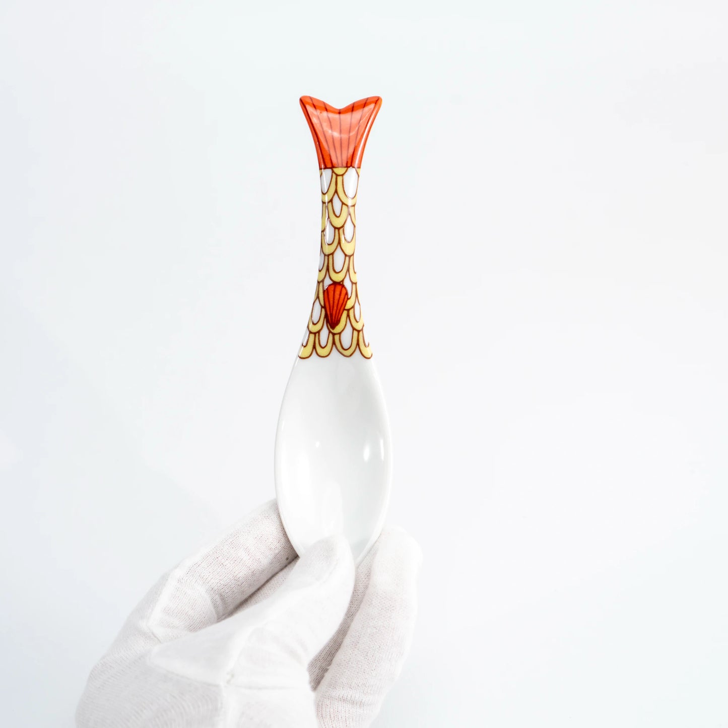 Hand-held yellow Kutani whale renge spoon showing the patterned whale-tail handle