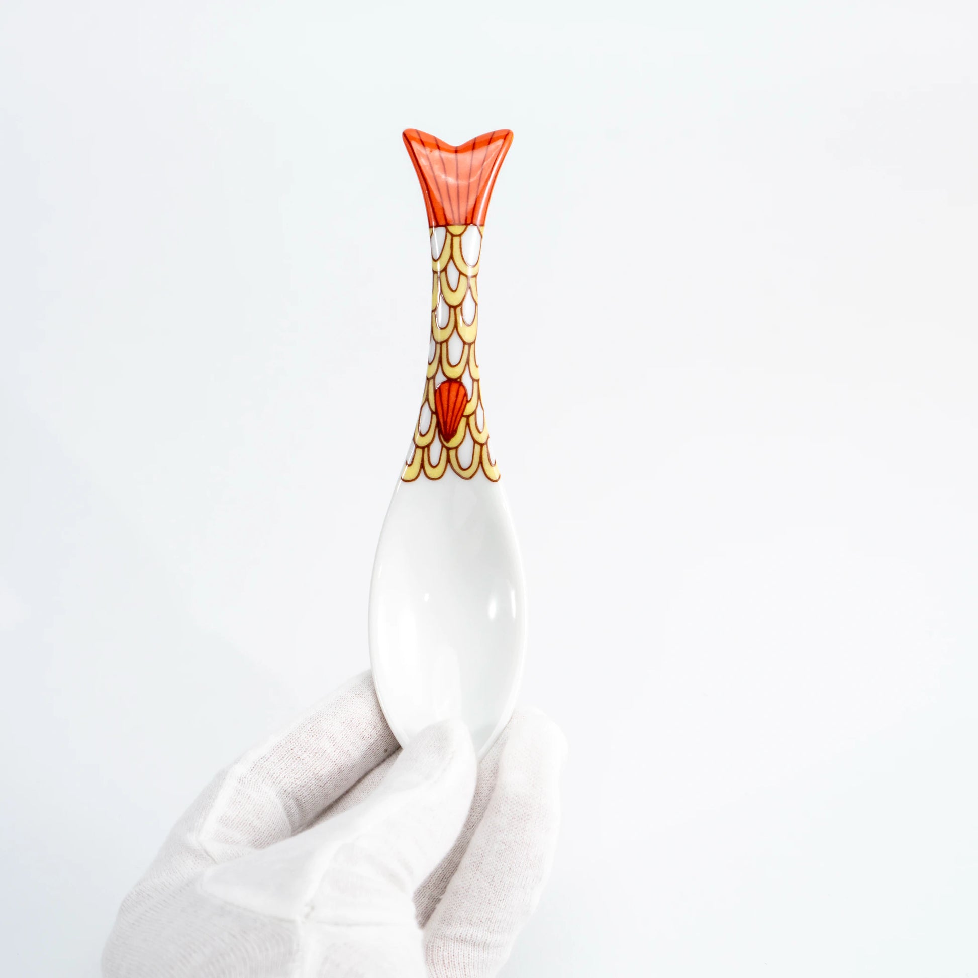 Hand-held yellow Kutani whale renge spoon showing the patterned whale-tail handle