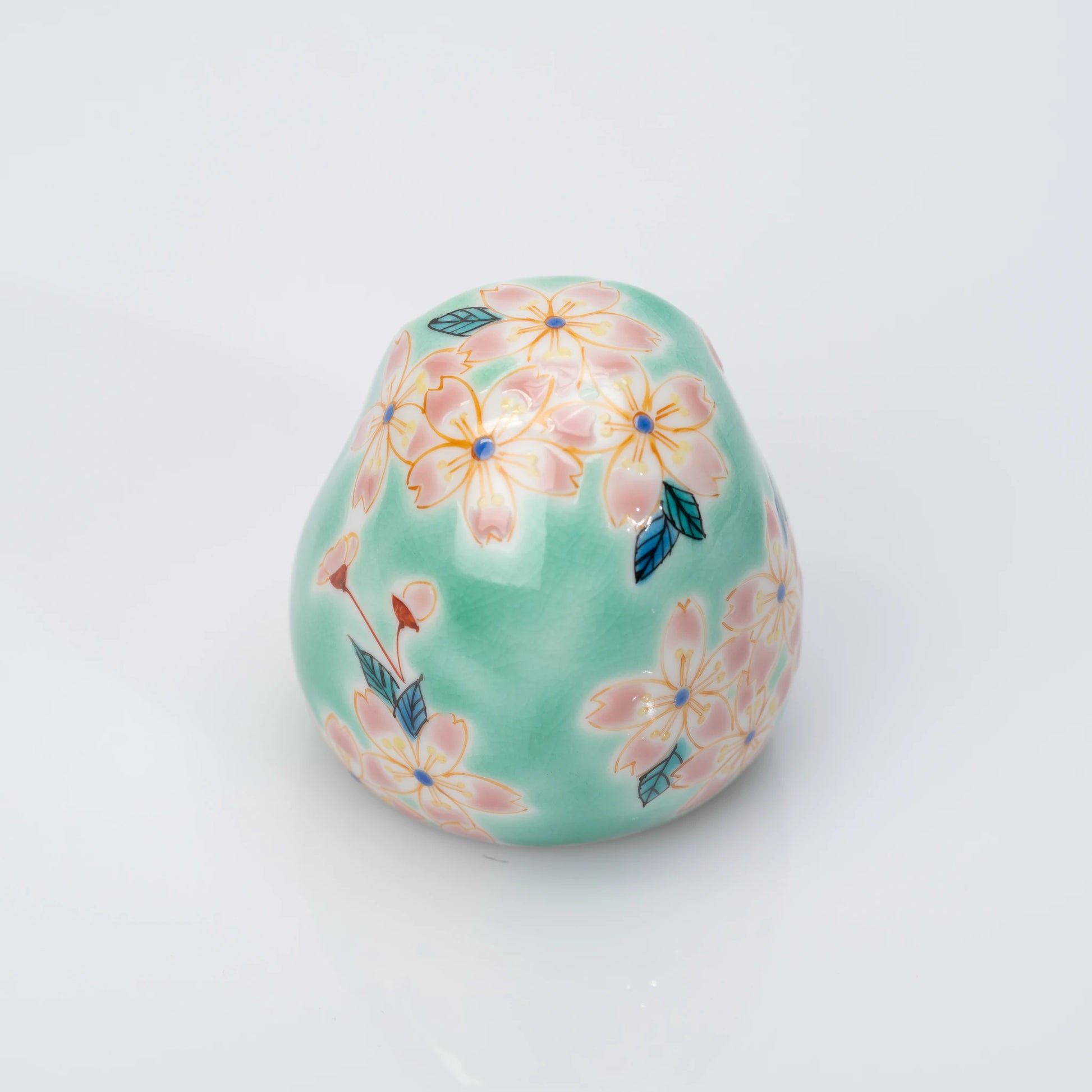 Back view of aqua Kutani Daruma covered in pink cherry blossoms