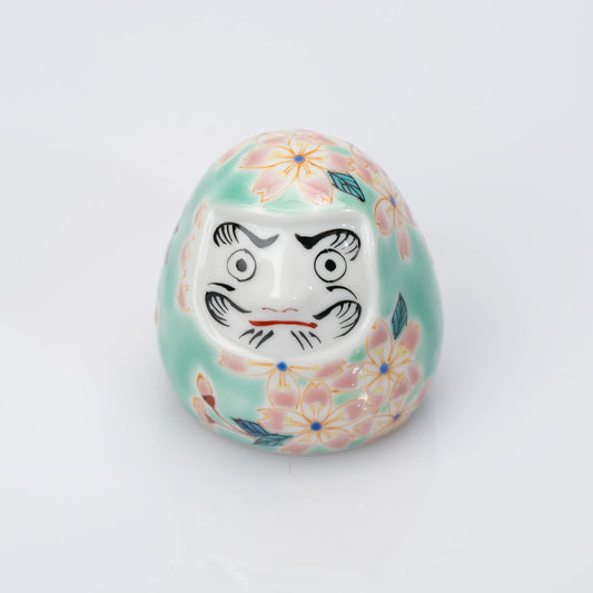 Angled front view of aqua Kutani Daruma with pink cherry blossoms