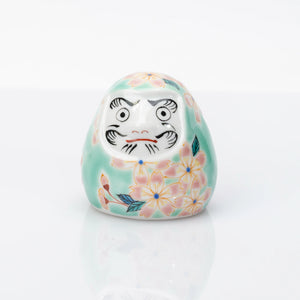 Vooraanzicht van aquakleurige Kutani-daruma met roze kersenbloesem