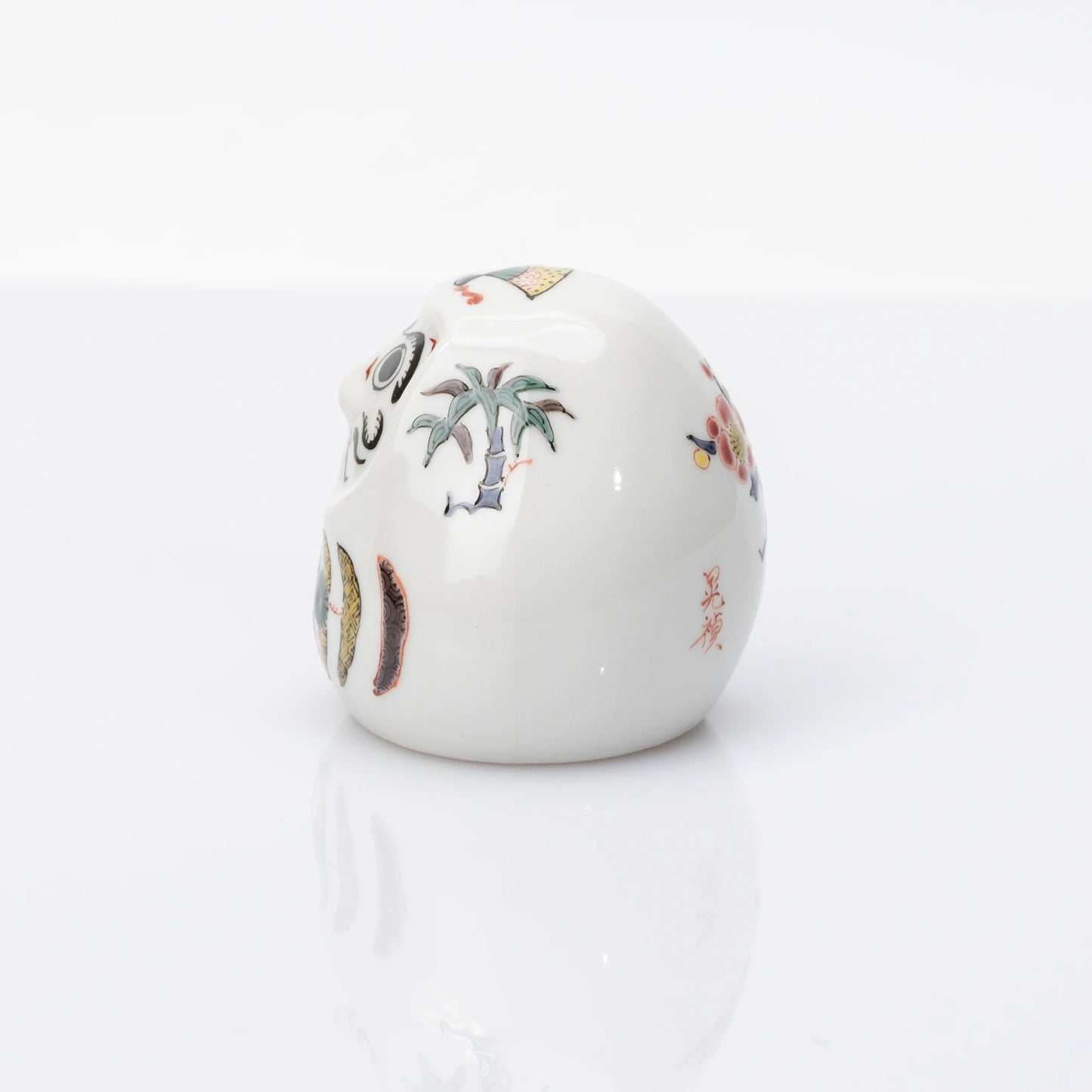 Side view showing bamboo and plum details on Kutani Daruma