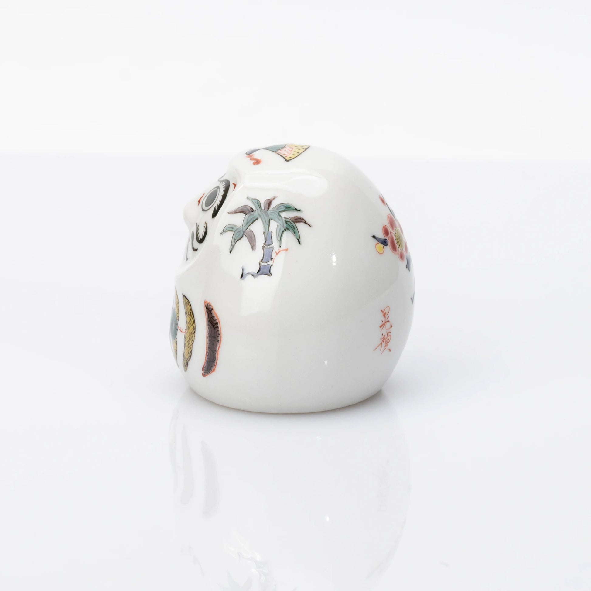 Side view showing bamboo and plum details on Kutani Daruma