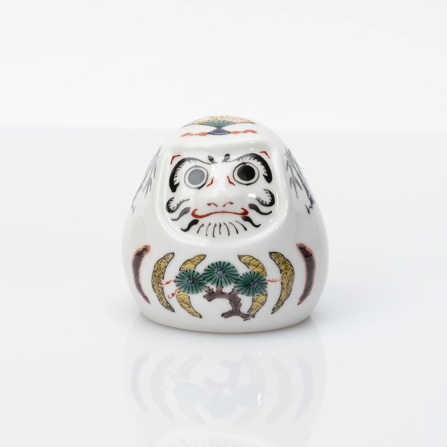 Front view of white Kutani Daruma with pine, bamboo and plum motifs
