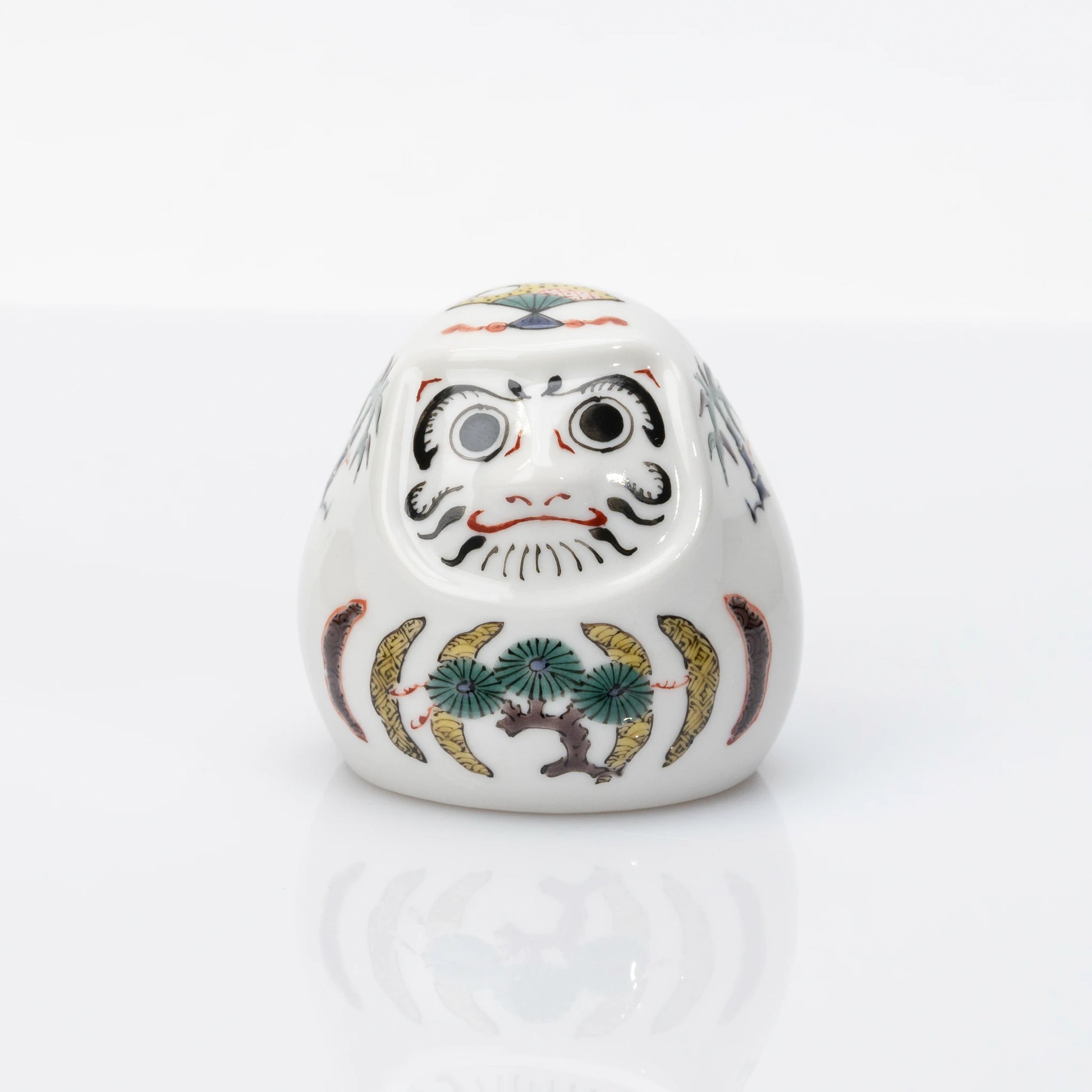 Front view of white Kutani Daruma with pine, bamboo and plum motifs