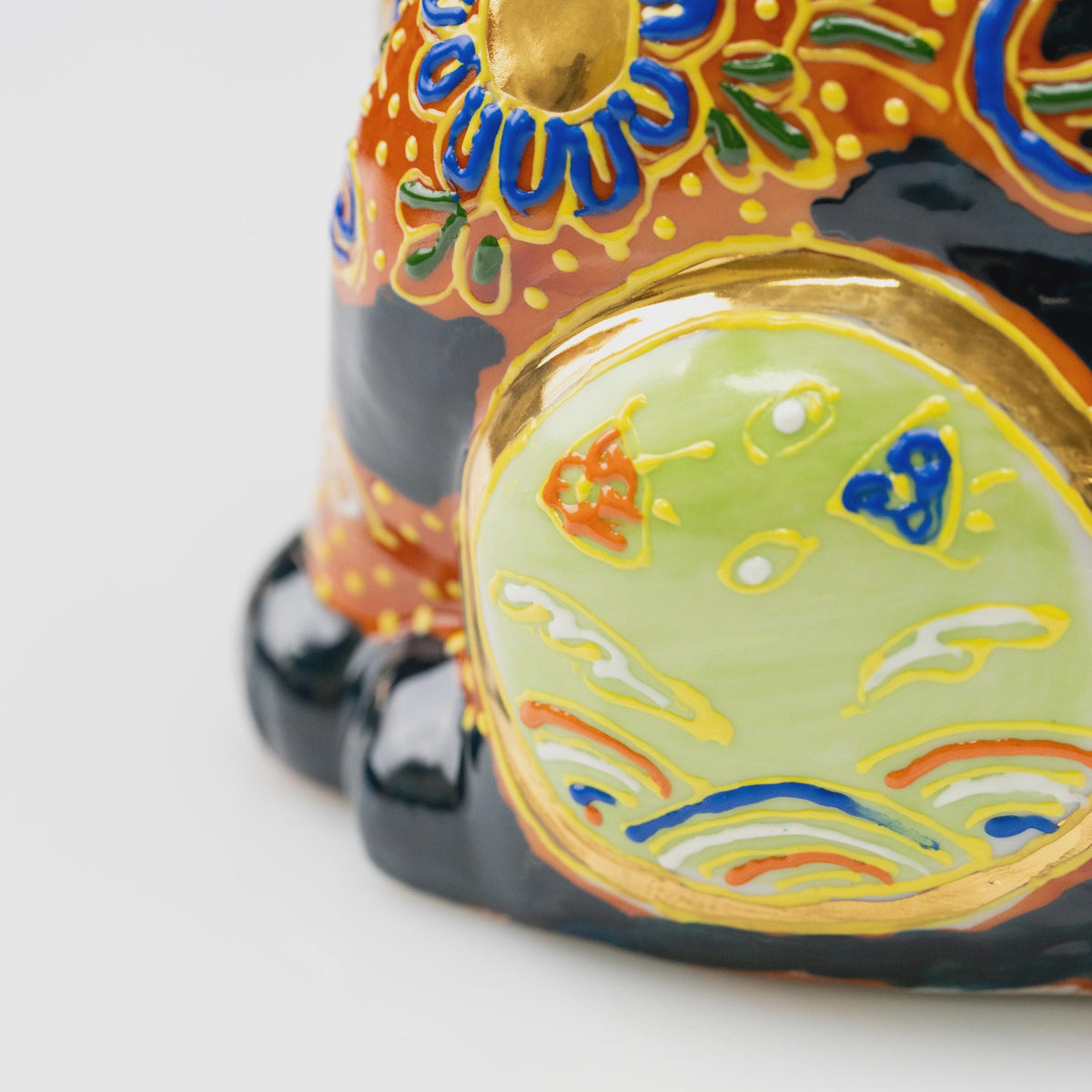 Close-up of the light green circular side panel with a gold-tone border, colorful motifs and curved lines.