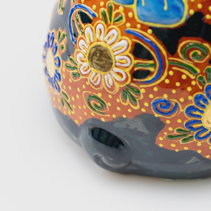Close-up of the curled black tail surrounded by colorful flowers, green spirals and raised yellow dots.