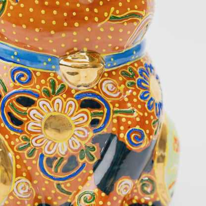 Close-up of the gold-tone bell on the blue collar above white floral decoration and raised yellow dots.