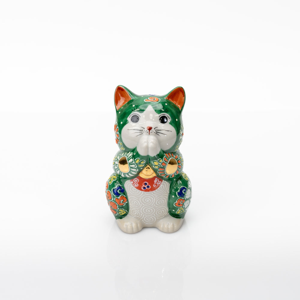 Front view of a green Kutani praying cat with joined white paws, raised floral patterns, and gold-colored accents.
